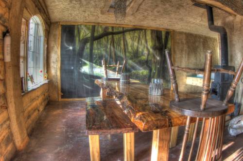 A rustic dining area with a wooden table, chairs, and a mural of a forest scene on the wall.