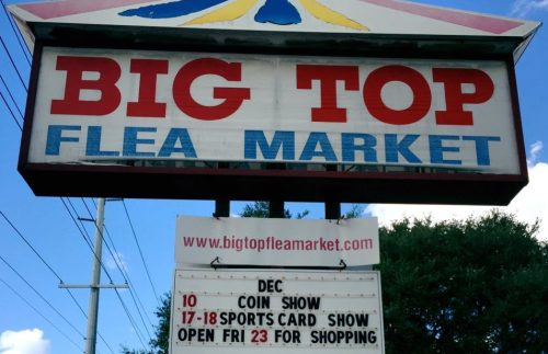 Sign for Big Top Flea Market featuring upcoming events: coin show, sports card show, and shopping hours.