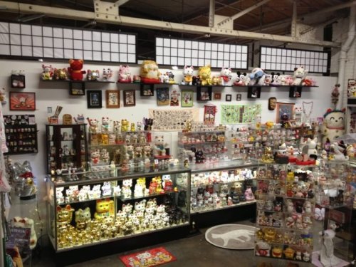 A colorful display of various figurines and collectibles, including many cat-themed items, in a well-lit shop.