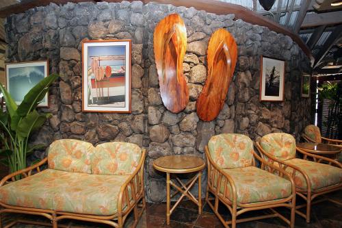 Cozy seating area with floral couches, a stone wall, and wooden art pieces in a tropical-themed interior.