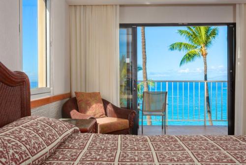 Cozy hotel room with a patterned bedspread, overlooking a balcony with palm trees and ocean views.