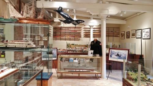 A display room featuring model ships, aircraft, and memorabilia, with glass cases and a military jacket on display.