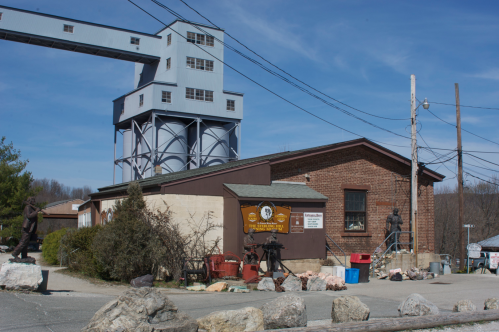 A historic building with a tall structure above, surrounded by rocks and power lines, under a clear blue sky.