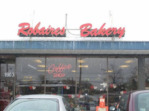 A bakery storefront with "Robaires Bakery" sign, snow falling, and a coffee shop sign visible in the window.
