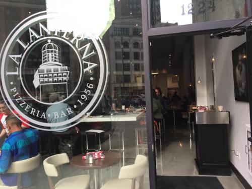 A view of La Lanterna pizzeria from outside, showcasing modern decor and diners inside.