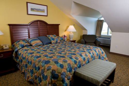 Cozy hotel room with a patterned bedspread, two lamps, a chair, and a window, featuring warm yellow walls.