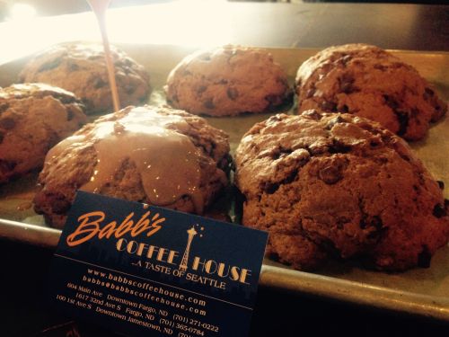 Freshly baked scones on a tray with a drizzle of glaze and a business card for Babbi's Coffee House.