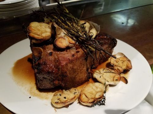 A succulent roast with roasted garlic and herbs, served on a white plate with a rich sauce.