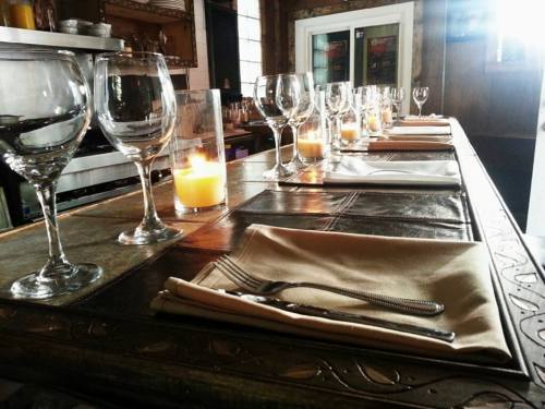 A beautifully set dining table with wine glasses, candles, and neatly arranged napkins.
