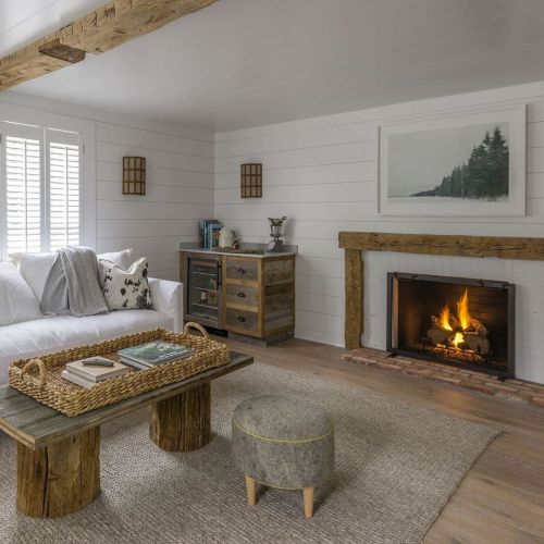 Cozy living room with a white sofa, rustic coffee table, and a fireplace, featuring natural wood accents and soft decor.