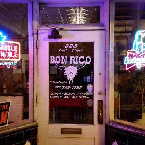 A restaurant entrance with neon signs, featuring the name "Bon Rico" and hours for lunch and dinner.