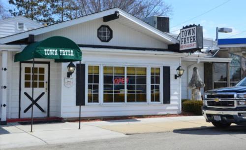 Exterior of Town Fryer restaurant with a green awning, open sign, and a parked truck in front.