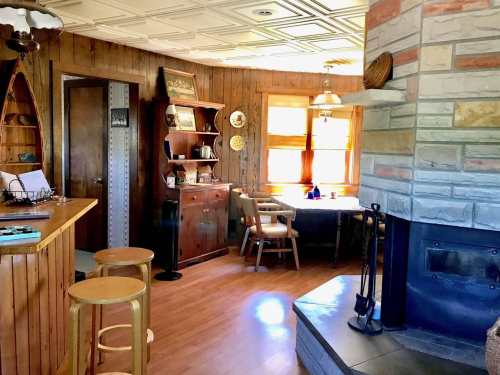 Cozy interior of a rustic home featuring wooden decor, a stone fireplace, and a dining area with natural light.