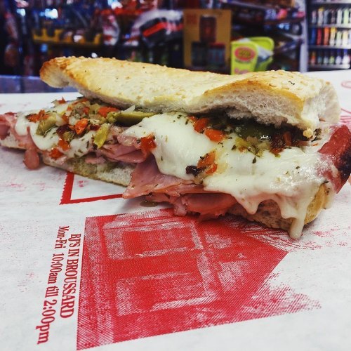 A large sandwich filled with ham, melted cheese, and herbs, served on a toasted hoagie roll.