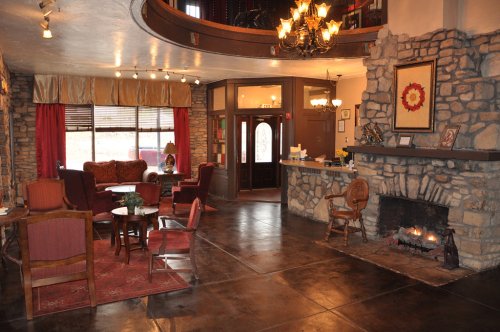 Cozy lobby with stone walls, a fireplace, comfortable seating, and warm lighting, creating an inviting atmosphere.