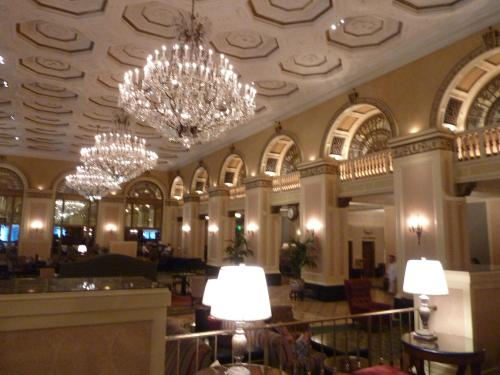 Elegant hotel lobby featuring ornate chandeliers, high ceilings, and classic architectural details.