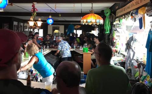 A lively bar scene with patrons enjoying drinks, colorful decor, and an alien-themed ambiance.