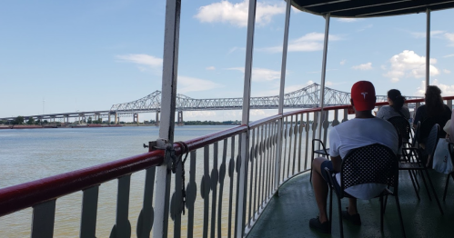 A view from a ferry showing a bridge over water, with passengers seated on the deck enjoying the scenery.