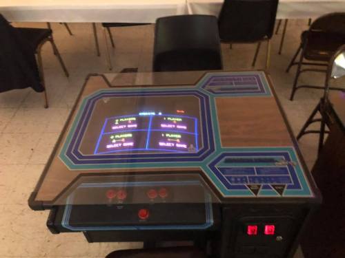 An arcade game table with a colorful screen displaying game options and control buttons.
