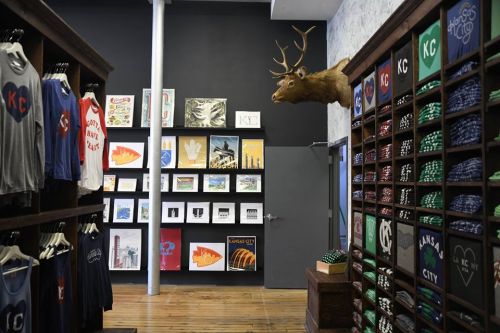 A stylish store interior featuring clothing racks, artwork on the walls, and a mounted deer head.
