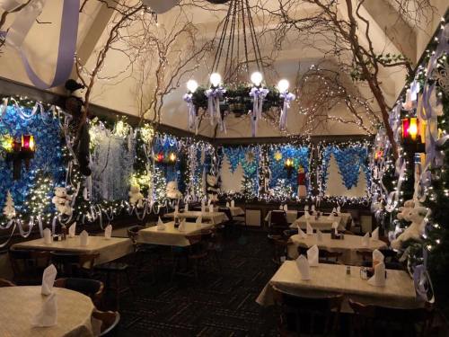 Cozy restaurant decorated for winter with blue and white lights, snowman figures, and festive table settings.