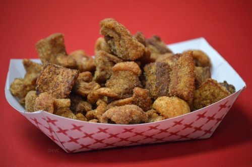 A basket filled with crispy, golden-brown fried food pieces on a red background.