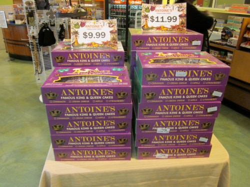 A display of colorful boxes of Antoine's King and Queen cakes, priced at $9.99 and $11.99, stacked on a table.