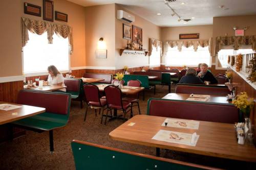 A cozy restaurant interior with empty booths, tables, and a few diners enjoying their meals. Warm lighting and decor.