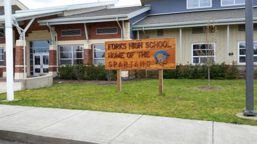 Sign for Forks High School, featuring a Spartan helmet, with the text "Home of the Spartans" in front of the school building.