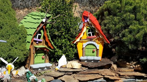 Colorful miniature houses with whimsical roofs, surrounded by greenery and decorative stones.