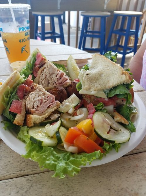 A plate with a sandwich filled with meat and lettuce, accompanied by a fresh salad of cucumbers and tomatoes.