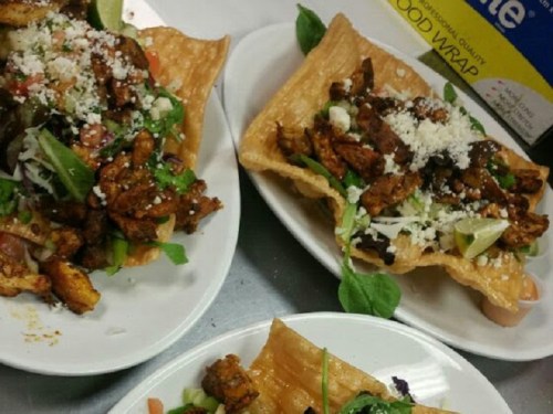 Three plates of crispy tostadas topped with seasoned chicken, lettuce, tomatoes, cheese, and lime wedges.