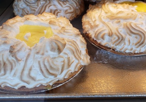 Two meringue-topped pies with a yellow filling, displayed on a silver tray.