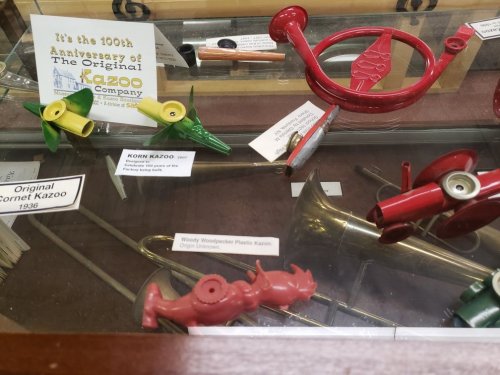 Display case featuring various kazoos, including a red Woody Woodpecker kazoo, celebrating the 100th anniversary of the Kazoo Company.