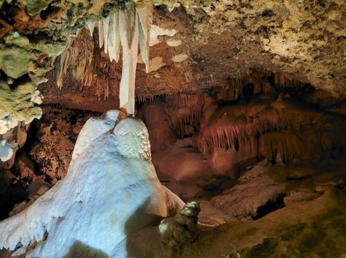 Stalactites and stalagmites in a dimly lit cave, showcasing unique rock formations and textures.