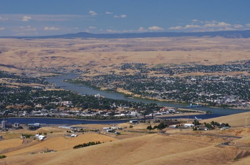 Aerial view of a river winding through a dry, hilly landscape with a small town along its banks.