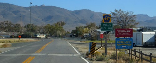 Road sign indicating the entrance to Gerlach, Nevada, with mountains in the background and a clear blue sky.