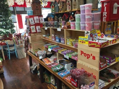 A colorful candy shop display with various sweets, jars, and treats arranged on wooden shelves.
