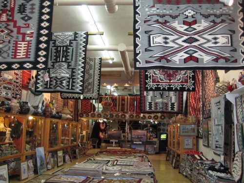 A vibrant store interior filled with hanging rugs and decorative items, showcasing intricate patterns and colors.
