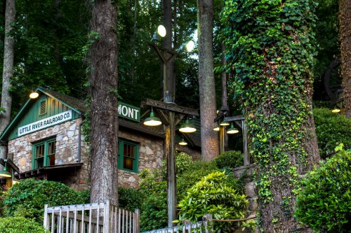 A rustic stone building surrounded by trees, with green accents and outdoor lights, labeled "Little River Railroad Co."