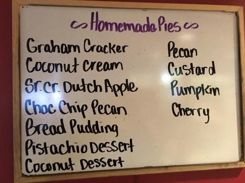 A whiteboard listing various homemade pies: Graham Cracker, Coconut Cream, Dutch Apple, Choc Chip Pecan, and more.