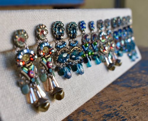 A display of colorful, ornate earrings arranged neatly on a textured surface.