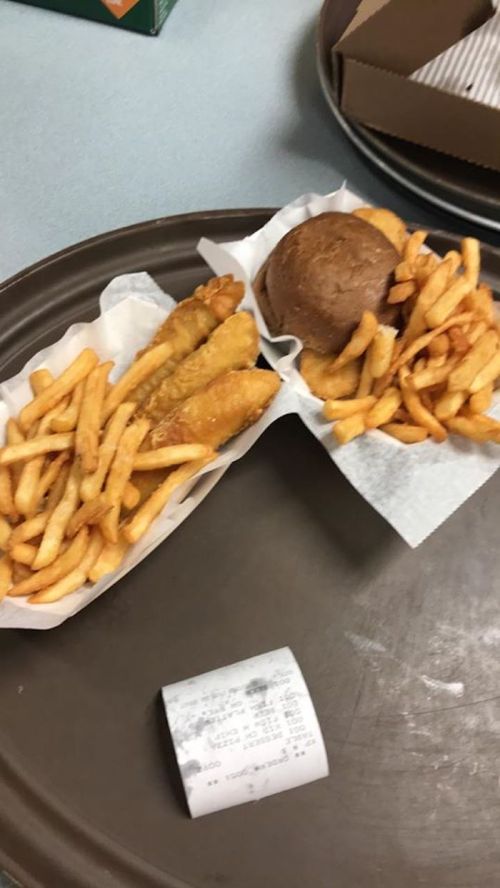 A tray with two servings of fries, fried fish, and a brown bun, alongside a receipt.