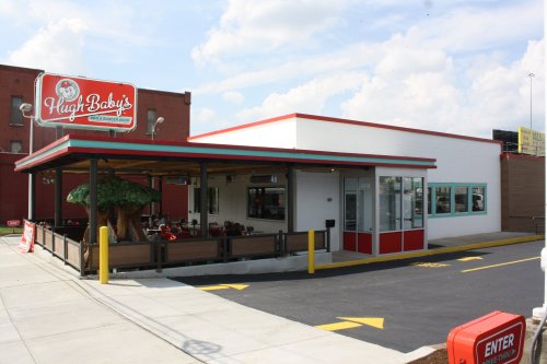 Exterior view of Hugh Baby's restaurant, featuring a red and white building with outdoor seating and a large sign.