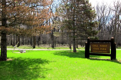 Sign for Gull Point State Park surrounded by green grass and trees, with a path leading into the park.