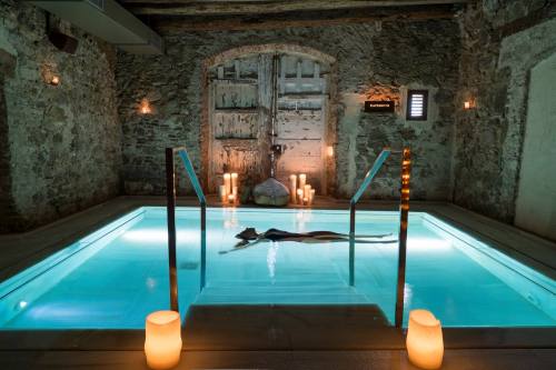 A serene spa setting with a person floating in a lit pool, surrounded by stone walls and glowing candles.