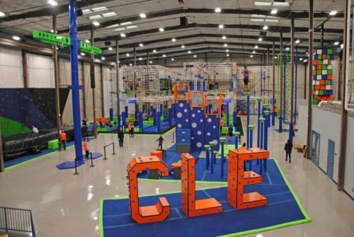 A vibrant indoor adventure park featuring climbing walls, obstacle courses, and colorful structures for active play.