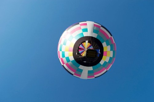 A colorful hot air balloon floats against a clear blue sky.