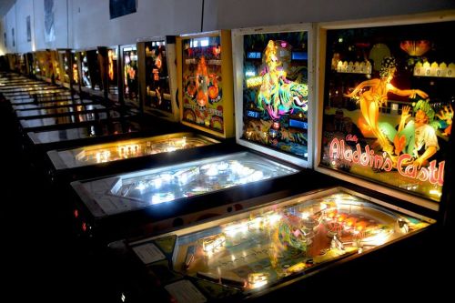 A row of illuminated pinball machines featuring colorful designs and vibrant artwork.