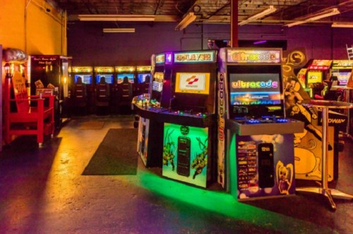 A vibrant arcade with colorful game machines and neon lights, featuring classic and modern arcade games.